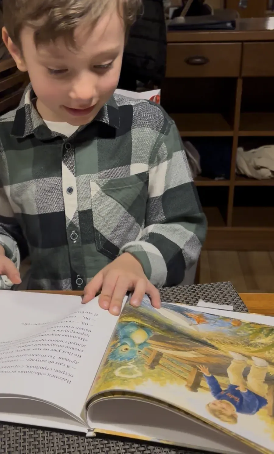 A boy smiling over a spread of his printed book